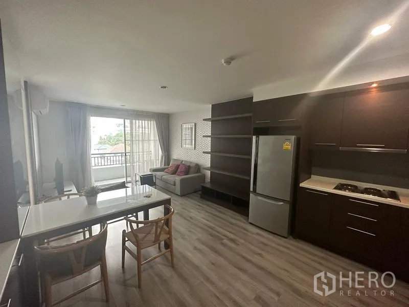 คอนโด ให้เช่า - ห้องครัวและมุมนั่งเล่น พร้อมชั้นบิลท์อิน มองออกไปยังระเบียง