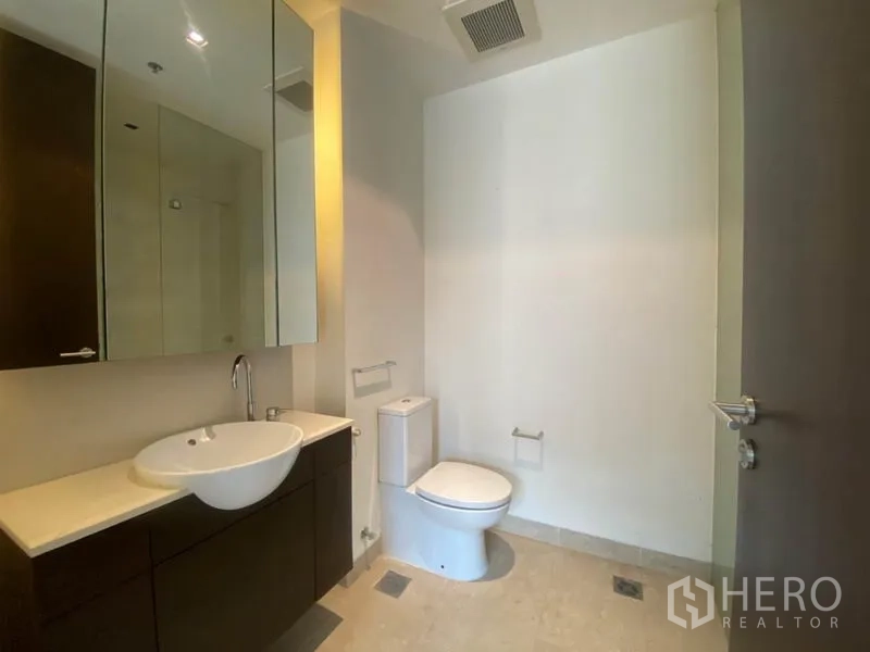 Condominium for rent in Yan Nawa, Bangkok - Bathroom with mirrored cabinet, vanity sink and toilet.