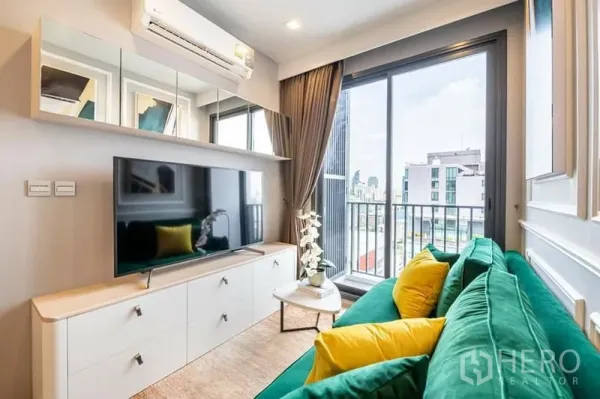 Condominium for rent or sale in Watthana, Bangkok - Bright living room with emerald green sofa, TV console and sliding glass doors opening to a balcony with city view.