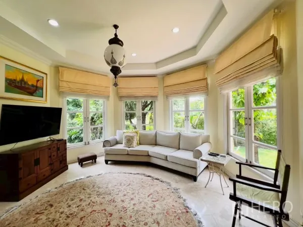 Detached House for rent in Prawet, Bangkok - Bright living room with bay windows, L-shaped sofa and TV cabinet.
