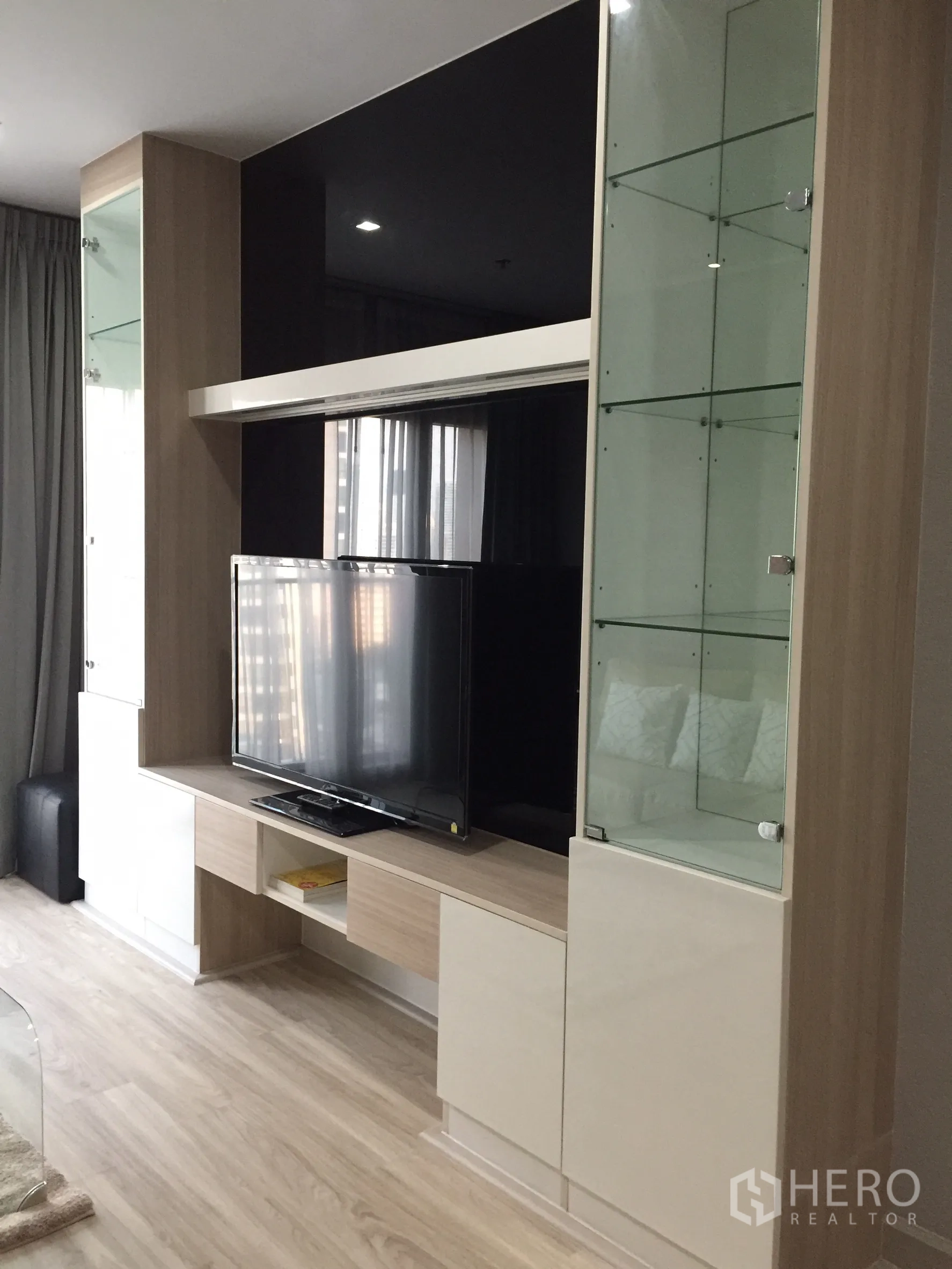 คอนโด ให้เช่าหรือขายในBangkok - ชั้นวางทีวีในห้องนั่งเล่นพร้อมตู้โชว์กระจกและทีวีจอแบน