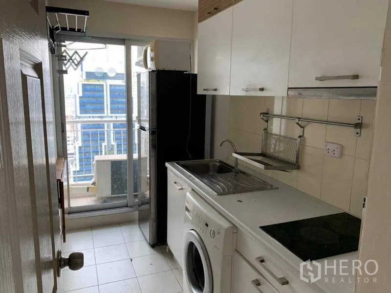 公寓 出租在Bang Rak, Bangkok - 狭长厨房配白色橱柜、水槽、洗衣机并可通往阳台。