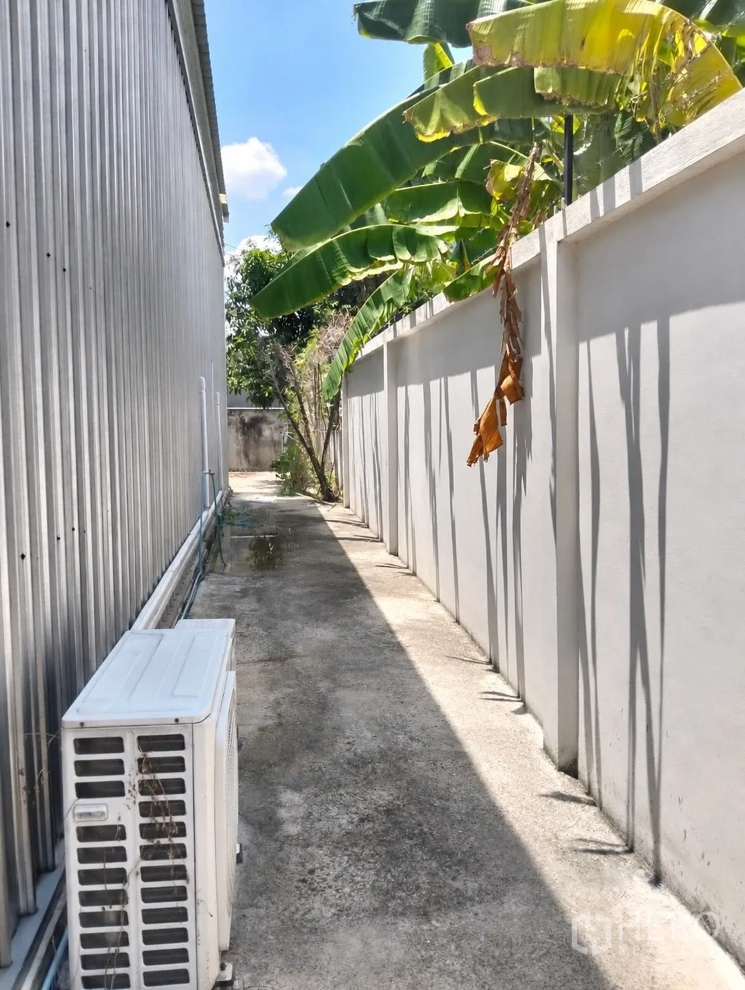 โกดัง for rent in Don Mueang, Bangkok - ทางเดินด้านข้างโกดัง มีกำแพงรั้ว ต้นไม้ และคอมเพรสเซอร์แอร์ภายนอก