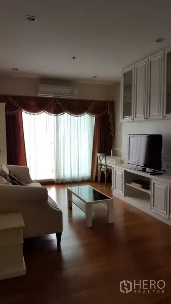 公寓 出租在Bang Rak, Bangkok - 客厅温馨，配沙发、电视柜与壁柜，落地玻璃门连通阳台与窗帘。