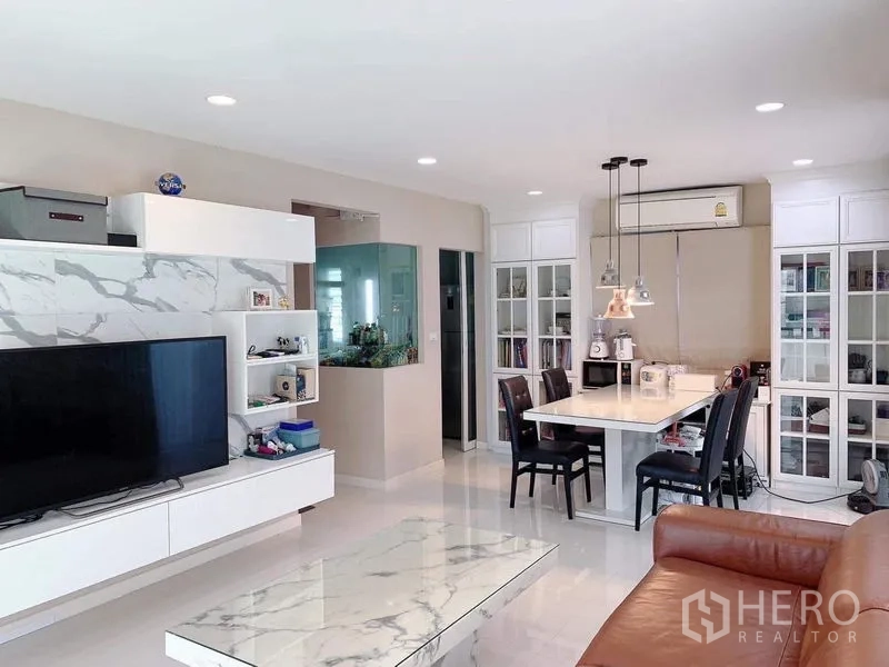 独立式住宅 出租或出售在Bang Phli, Samut Prakan - 客厅角度，电视墙为大理石纹，餐桌与吊灯相连