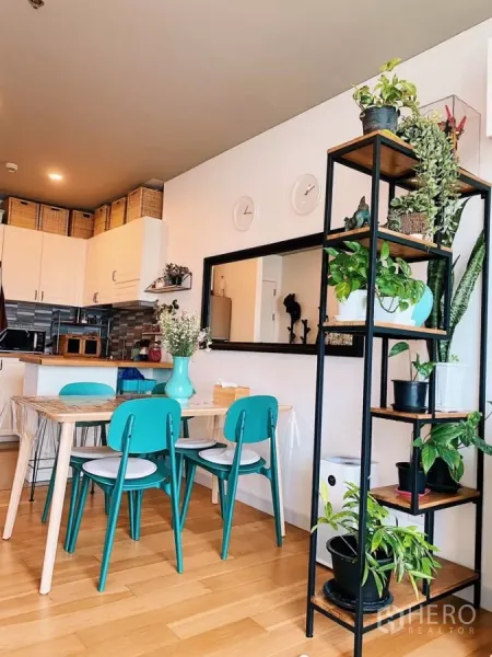 Condominium for rent in Watthana, Bangkok - Open-plan dining facing white kitchen with metal plant shelves and warm wooden floors.