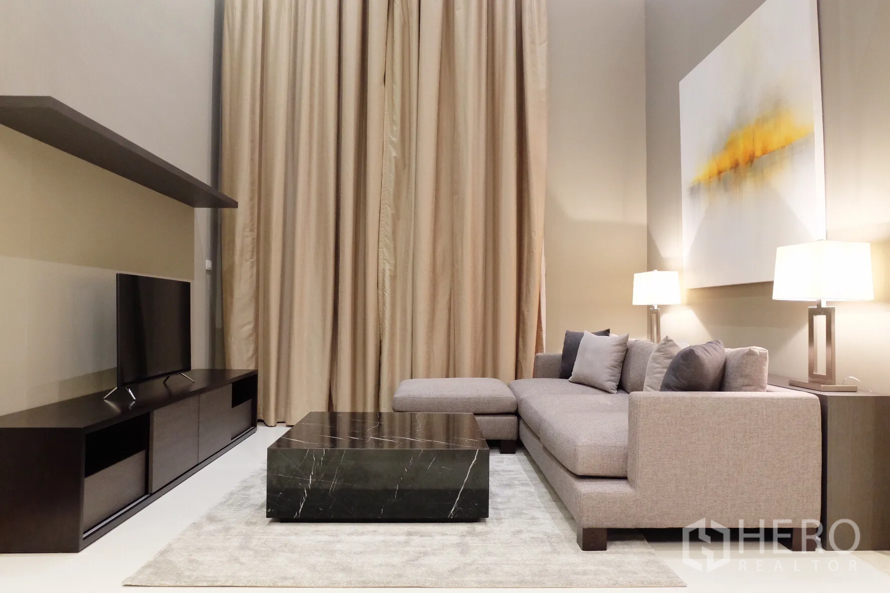 Condominium for rent in Sathon, Bangkok - Modern living room with high ceilings, L-shaped sofa, black marble coffee table, TV console and floor-to-ceiling curtains.