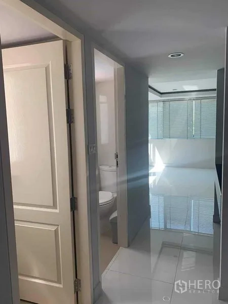 Townhouse for rent or sale in Yan Nawa, Bangkok - Hallway with bathroom access and bright room featuring blinds and tiled floor.