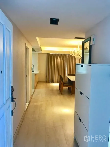 Condominium for rent or sale in Watthana, Bangkok - Entrance corridor with storage cabinet leading to dining area and kitchen under recessed lighting.