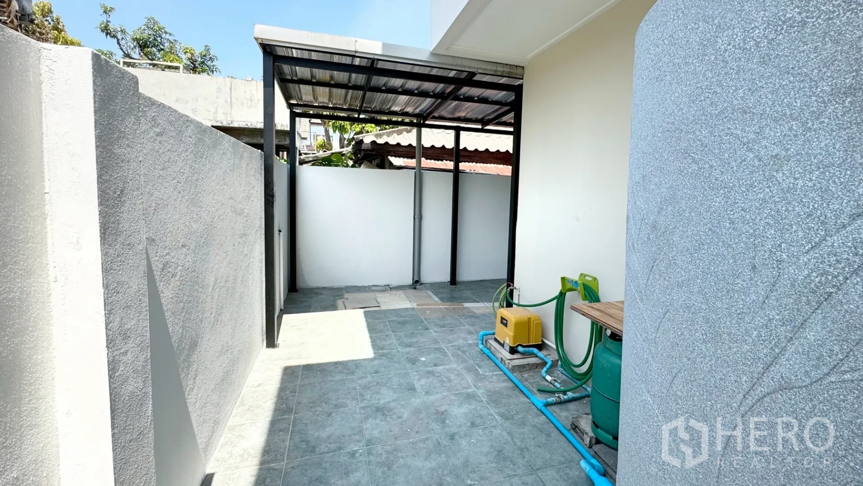 独栋房屋 for rent in Suan Luang, Bangkok - 后部服务庭院，部分加盖，高墙围合，设有水泵与燃气放置区。