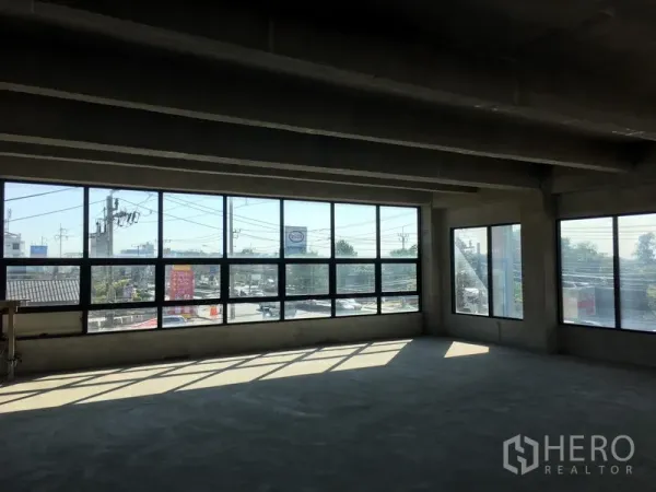 Home Office for rent in Lat Krabang, Bangkok - Open‑plan office floor with expansive corner windows providing abundant natural light and views over the nearby roadway.