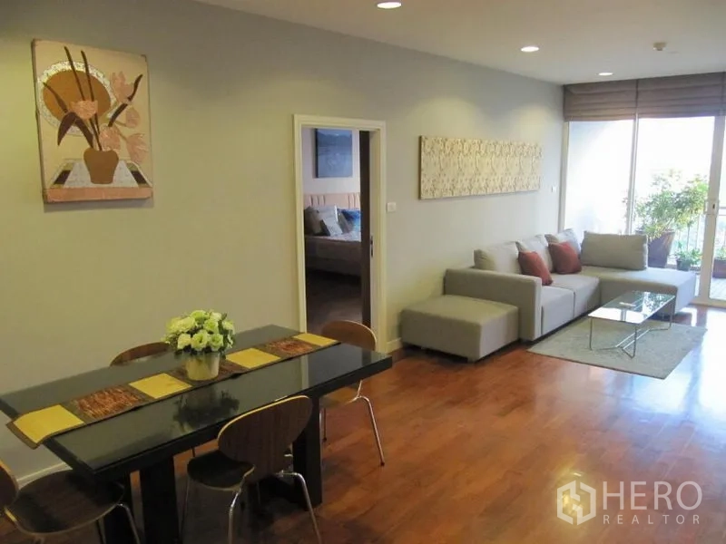 คอนโด ให้เช่าในKhlong Toei, Bangkok - มุมรับประทานอาหาร 4 ที่นั่ง มองไปยังห้องนั่งเล่นและระเบียง มีงานศิลปะผนังและพื้นไม้