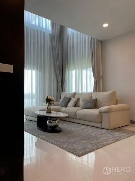 Detached House for rent or sale in Bang Phli, Samut Prakan - Cozy living area with cream sofa, round coffee table, and tall sheer curtains.