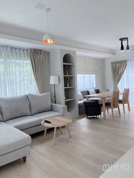 联排别墅 出租在Prawet, Bangkok - 舒适客厅，转角沙发、拱形置物架与餐椅区。