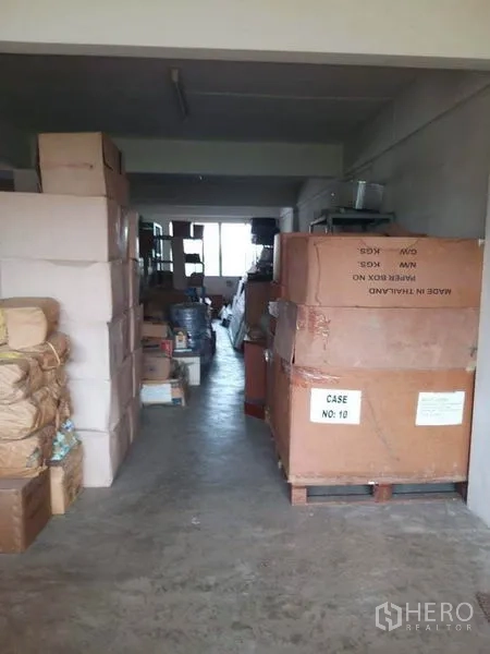 零售空间 出售在Bang Khun Thian, Bangkok - 纵深储物间，水泥地面，纸箱堆放在托盘上。