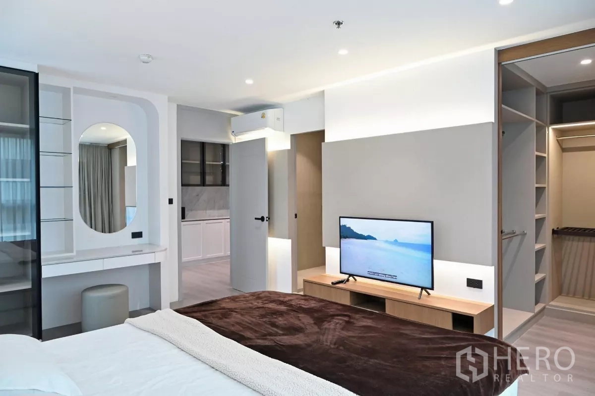 Condominium for rent in Watthana, Bangkok - Master bedroom with TV console, soft lighting and access to a walk-in closet at Sukhumvit Living Town.