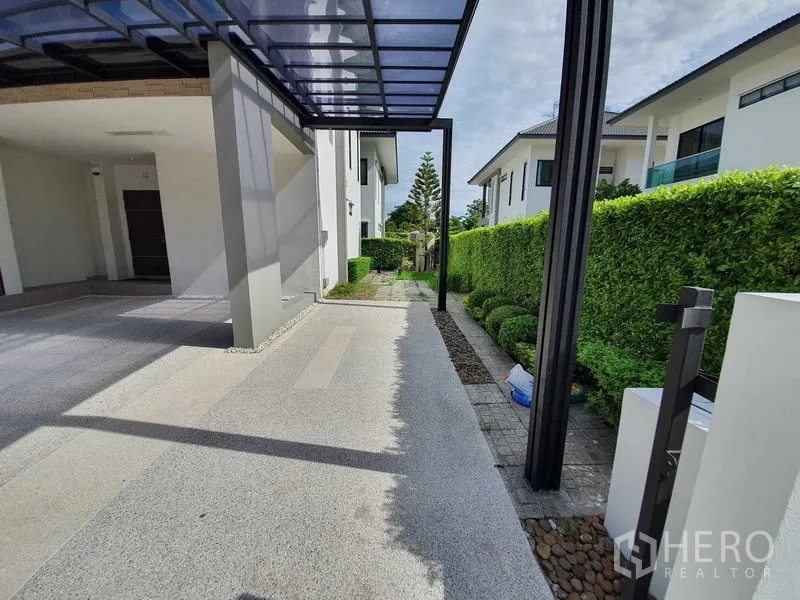 Detached House for sale in Bang Khun Thian, Bangkok - Side walkway and canopy carport bordered by manicured hedges.