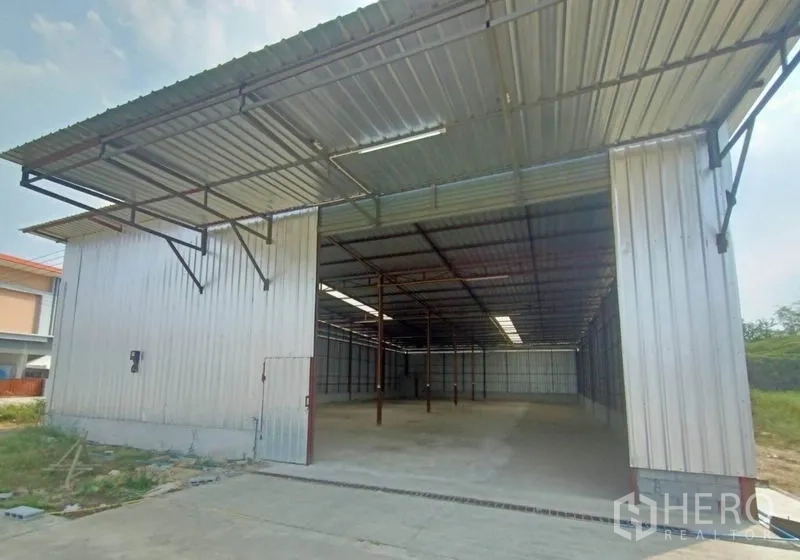 货栈 出租在Mueang Samut Sakhon, Samut Sakhon - 仓库正面，大开口入口位于金属雨棚下方。