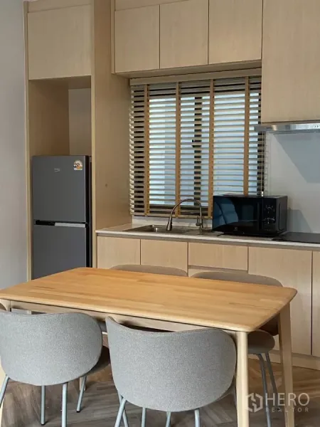 Townhouse for rent in Bang Phli, Samut Prakan - Close-up of kitchen window, sink, microwave and ample light-wood cabinetry.