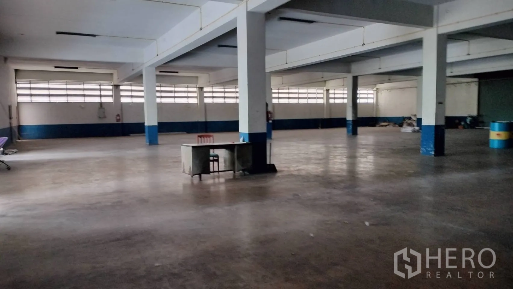 Factory for rent in Lat Krabang, Bangkok - Large interior floor space with pillars, fluorescent lighting, and a work desk in the center.