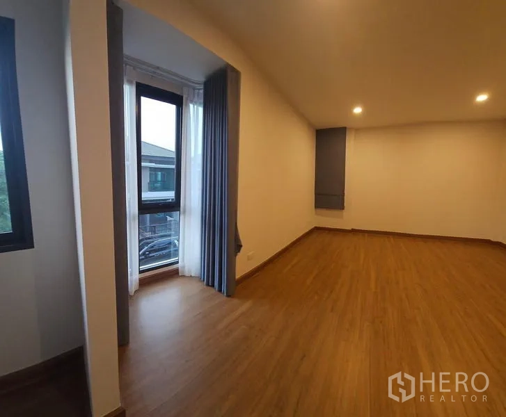 บ้าน ให้เช่าในSaphan Sung, Bangkok - ห้องนอนหลักขนาดใหญ่ มุมหน้าต่างยื่น ผ้าม่านครบ และพื้นลายไม้โทนอุ่น.