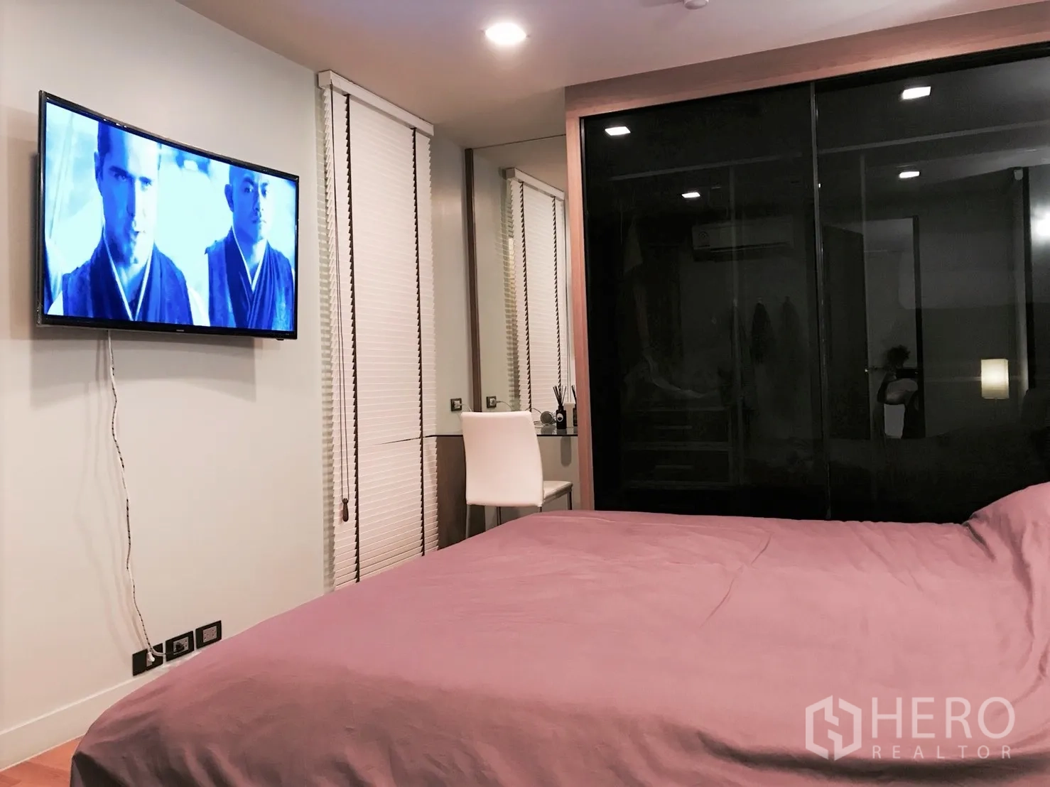Condominium for rent or sale in Bang Rak, Bangkok - Cozy bedroom with a wall-mounted TV, large bed, work desk, and black glass sliding wardrobe.
