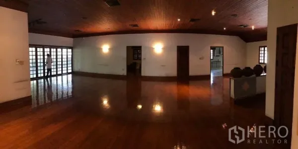 บ้าน ขายในBang Na, Bangkok - ห้องนั่งเล่นกว้าง พื้นไม้ขัดเงา เพดานไม้ และประตูกระจกบานเฟรนช์ยาวทั้งผนัง