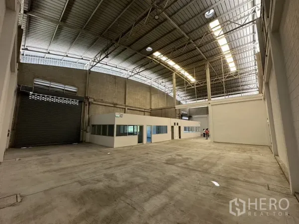 Factory for rent in Bang Phli, Samut Prakan - Clear-span interior showing roller door access and bright roof panels.