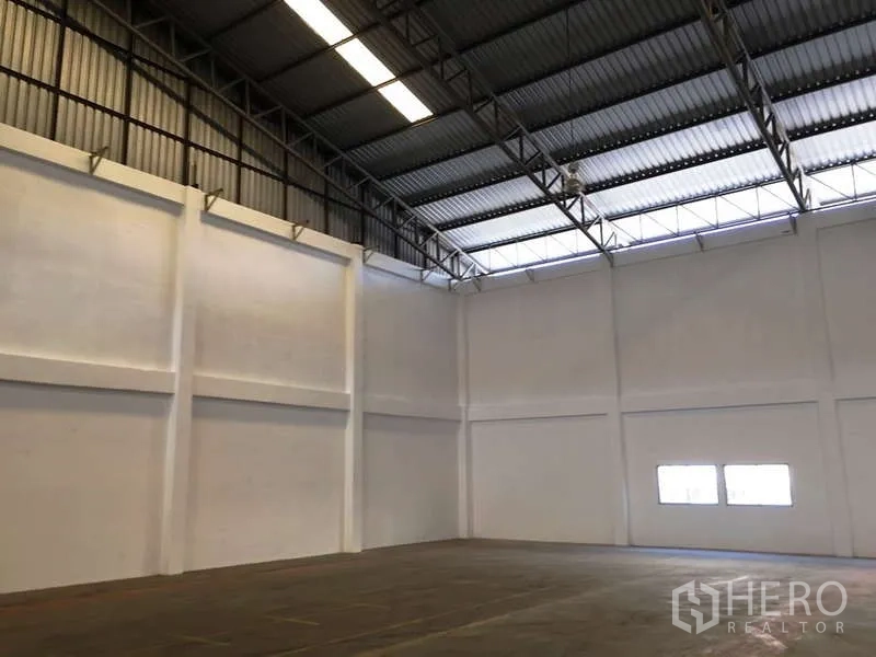 Factory for rent in Bang Bo, Samut Prakan - High-clearance steel truss roof with skylight panels over open production area.