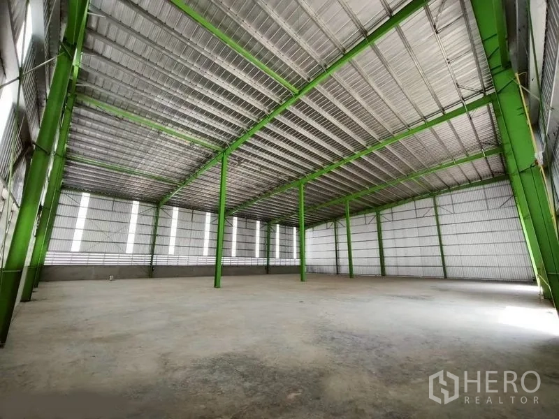 货栈 出租在Bang Phli, Samut Prakan - 仓库内部视角，高挑屋顶与绿色钢柱，开阔的混凝土地面。