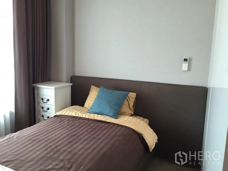 Condominium for rent in Ratchathewi, Bangkok - Bedroom with single bed, bedside cabinet and large window with blackout curtains.