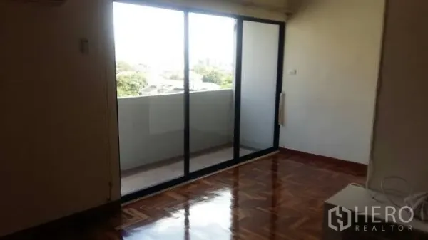 Condominium for rent in Watthana, Bangkok - Bright living area with sliding glass doors opening to a balcony.