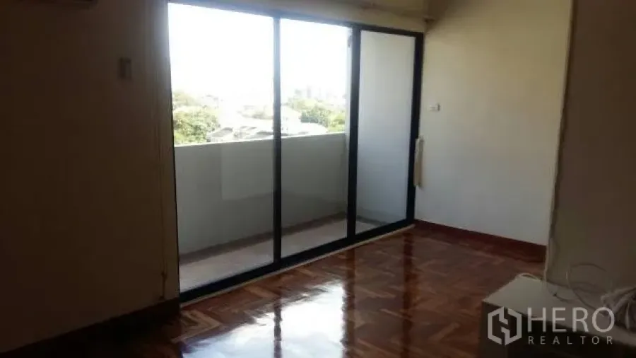 Condominium for rent in Watthana, Bangkok - Bright living area with sliding glass doors opening to a balcony.