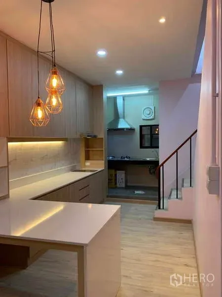 Townhouse for rent - Kitchen walkway toward a separate wet kitchen with warm pendant lighting and ample storage.