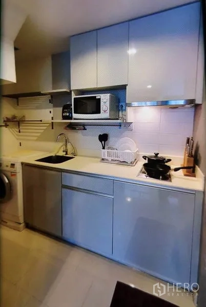 Condominium for rent in Phra Khanong, Bangkok - Compact built‑in kitchen with stove, microwave and washing machine.