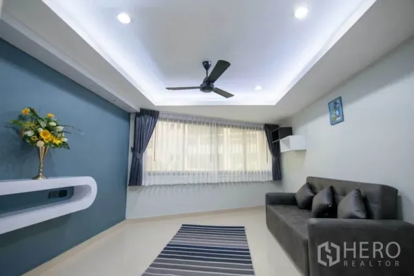 公寓 出租在Khlong Toei, Bangkok - 采光充足的客厅，托盘吊顶、吊扇、蓝色背景墙与灰色沙发，地毯点缀。