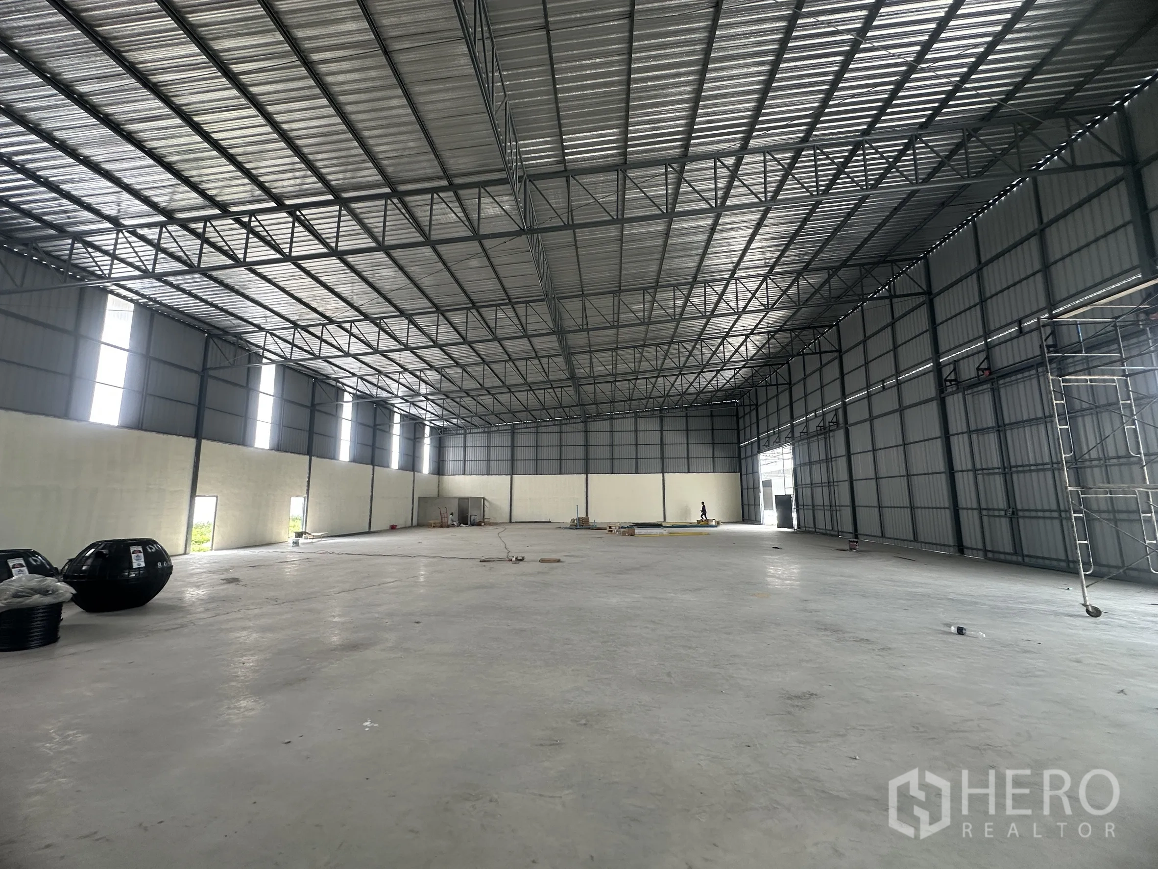 Warehouse for rent in Lam Luk Ka, Pathum Thani - Open warehouse hall with high roof, concrete slab, and vertical windows along the wall.