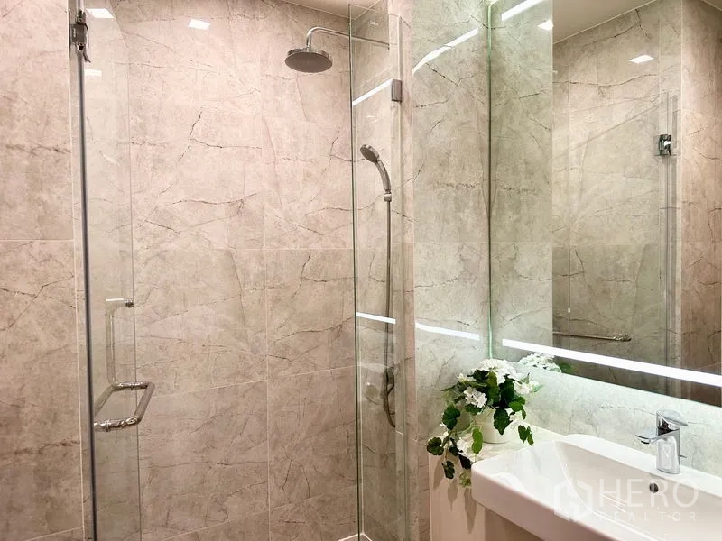 公寓 出租在Watthana, Bangkok - 淋浴间设雨淋与手持花洒，旁为简洁盥洗台。