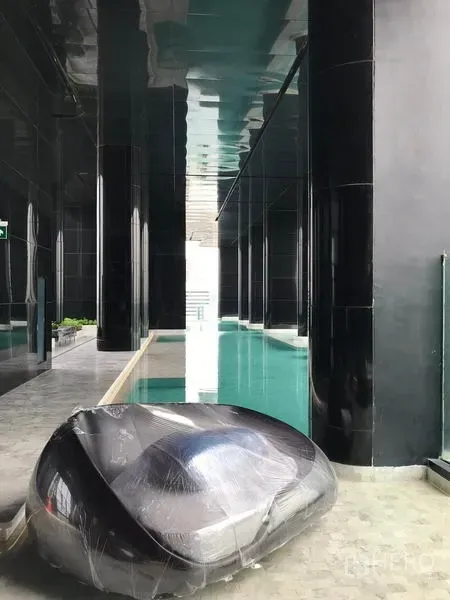 คอนโด ให้เช่าในWatthana, Bangkok - สระว่ายน้ำในอาคารดีไซน์หรู คอลัมน์สีดำ และเก้าอี้เลาจน์ร่วมสมัยข้างสระ