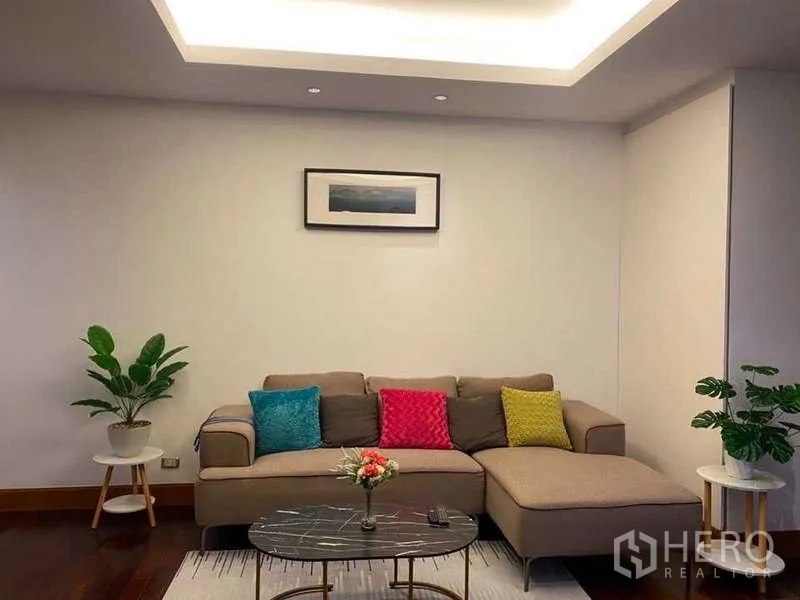 คอนโด ขายในSathon, Bangkok - ห้องนั่งเล่นอบอุ่น โซฟาเข้ามุม หมอนสีสัน และไฟฝ้าซ่อนแสง.