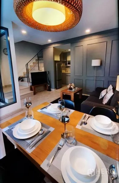 Condominium for rent in Phra Khanong, Bangkok - Dining table set for four under rattan pendant, overlooking living room.