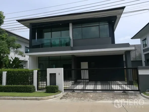 Detached House for rent in Bang Kapi, Bangkok - Modern two-storey detached house with gated driveway, balcony and large windows in a landscaped estate.