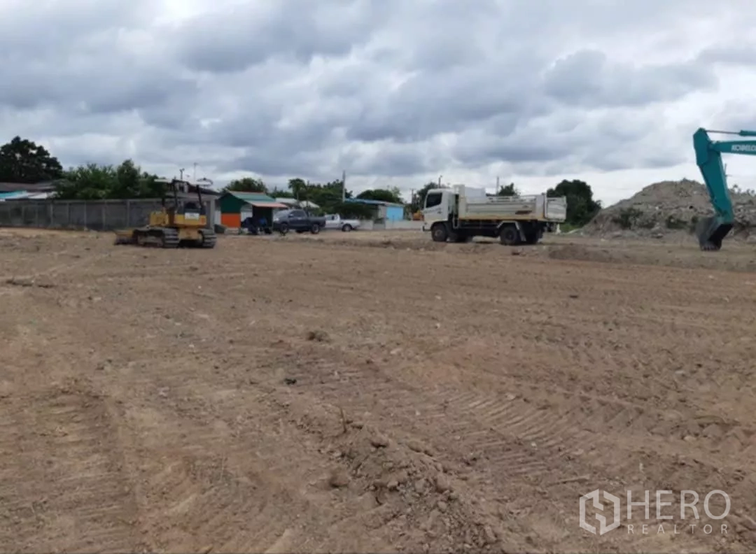 Land for sale in Khlong Toei, Bangkok - Compacted soil yard with heavy machinery and a truck on site.