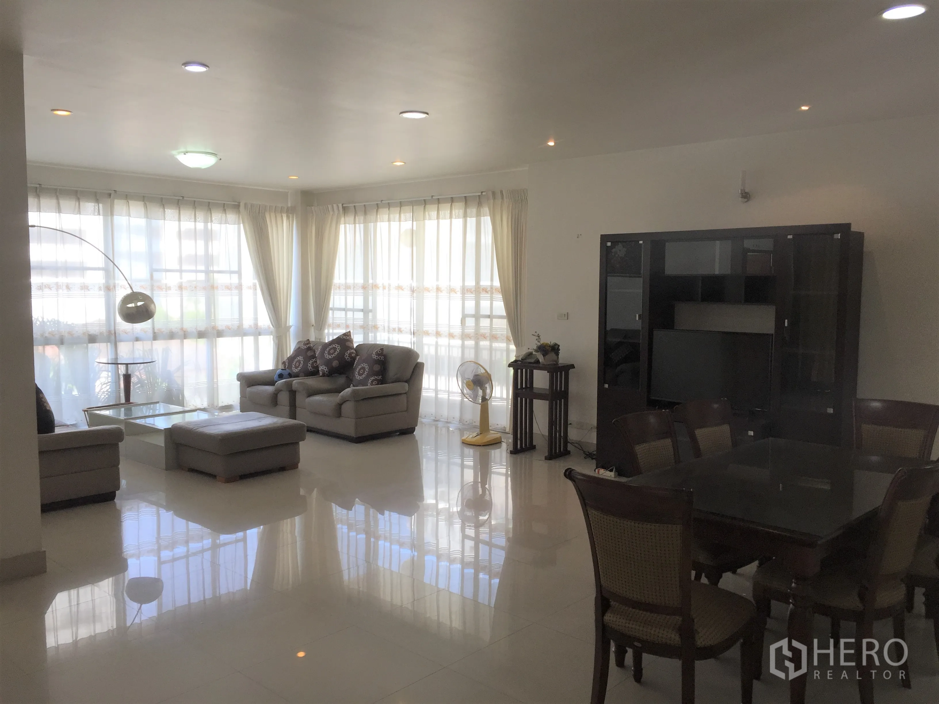 Condominium for rent in Watthana, Bangkok - Open-plan living and dining room with floor-to-ceiling windows, sheer curtains, sofas and a glass coffee table.