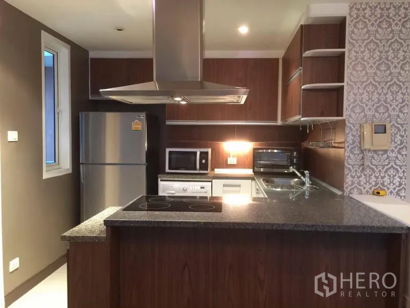 Condominium for rent in Watthana, Bangkok - Fully equipped kitchen with island cooktop, range hood and stainless-steel appliances.