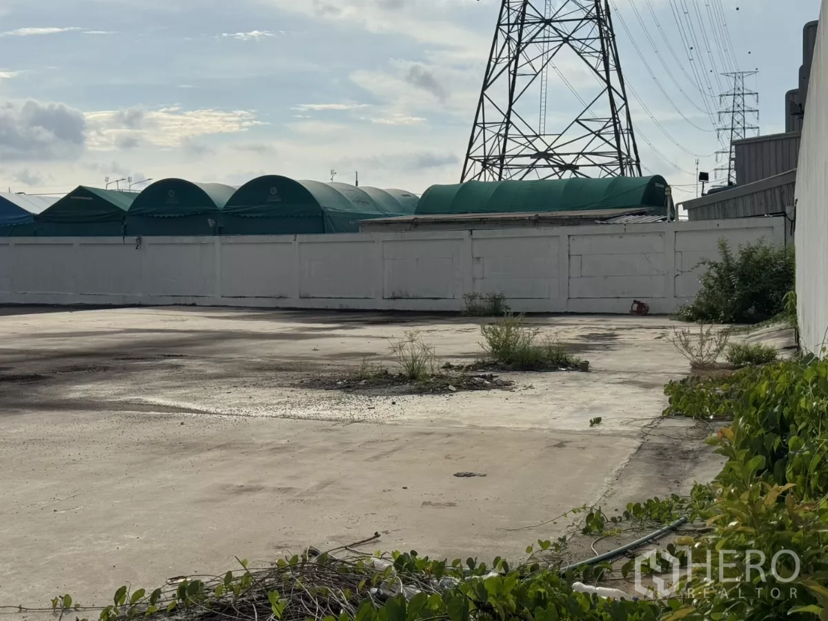 工厂 出租或出售在Bang Phli, Samut Prakan - 露天场地，旁有高压电塔与绿色棚顶。