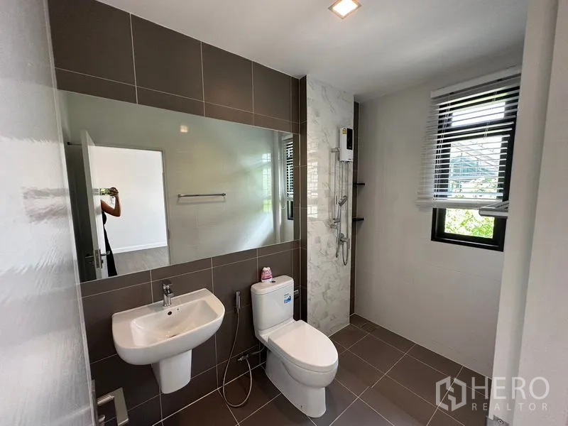Detached House for rent or sale - Bathroom with long mirror, window and a walk-in shower with water heater.