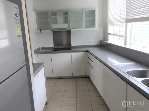 คอนโด ให้เช่าหรือขายในKhlong Toei, Bangkok - ครัวปิดสไตล์โมเดิร์น เคาน์เตอร์หินแกรนิตยาว ตู้สีขาว อ่างล้างจานคู่ และมู่ลี่หน้าต่าง