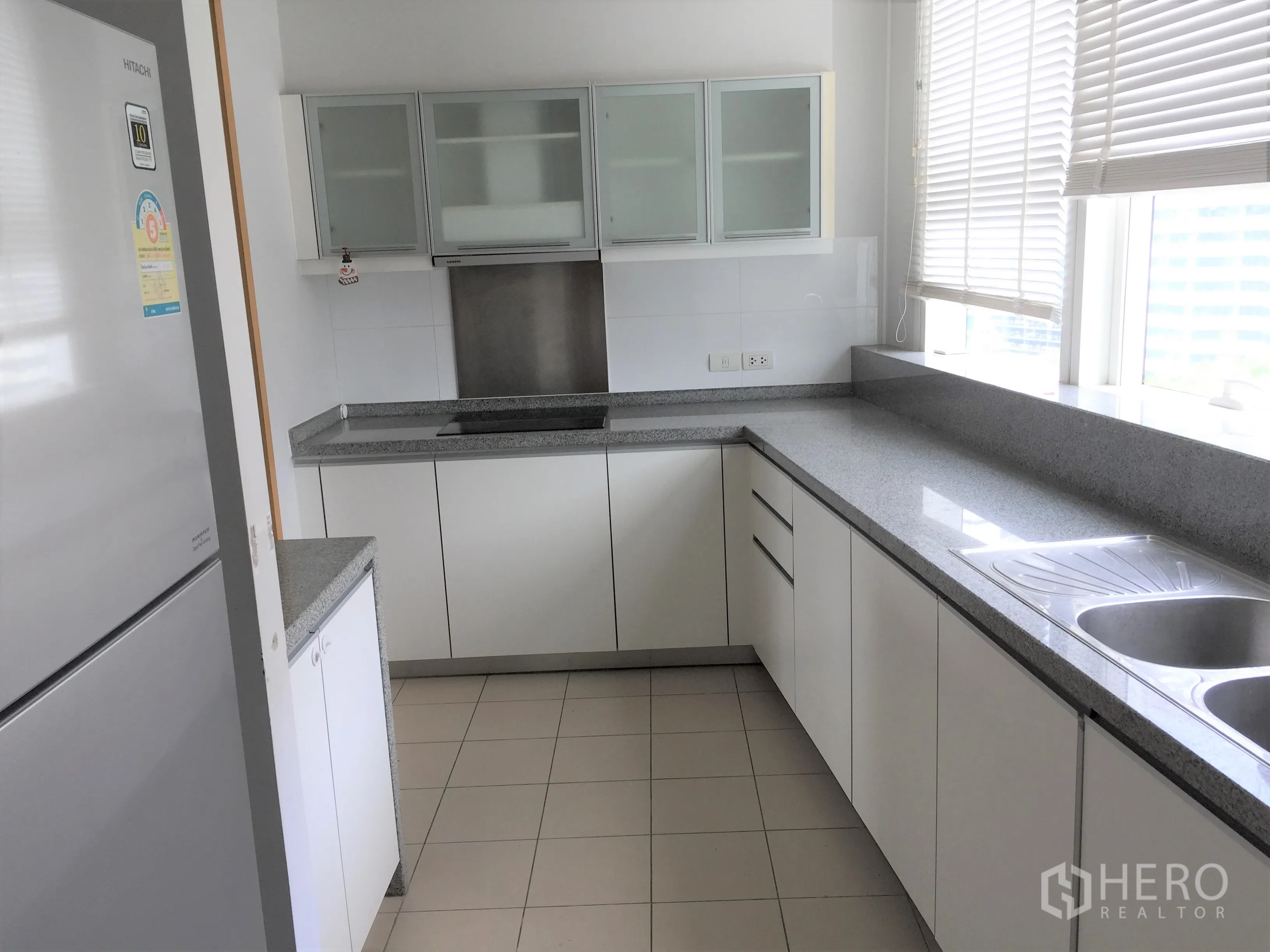 คอนโด ให้เช่าหรือขายในKhlong Toei, Bangkok - ครัวปิดสไตล์โมเดิร์น เคาน์เตอร์หินแกรนิตยาว ตู้สีขาว อ่างล้างจานคู่ และมู่ลี่หน้าต่าง