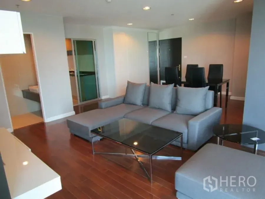 Condominium for sale in Huai Khwang, Bangkok - Spacious living room with sectional sofa, glass coffee table, and recessed lighting